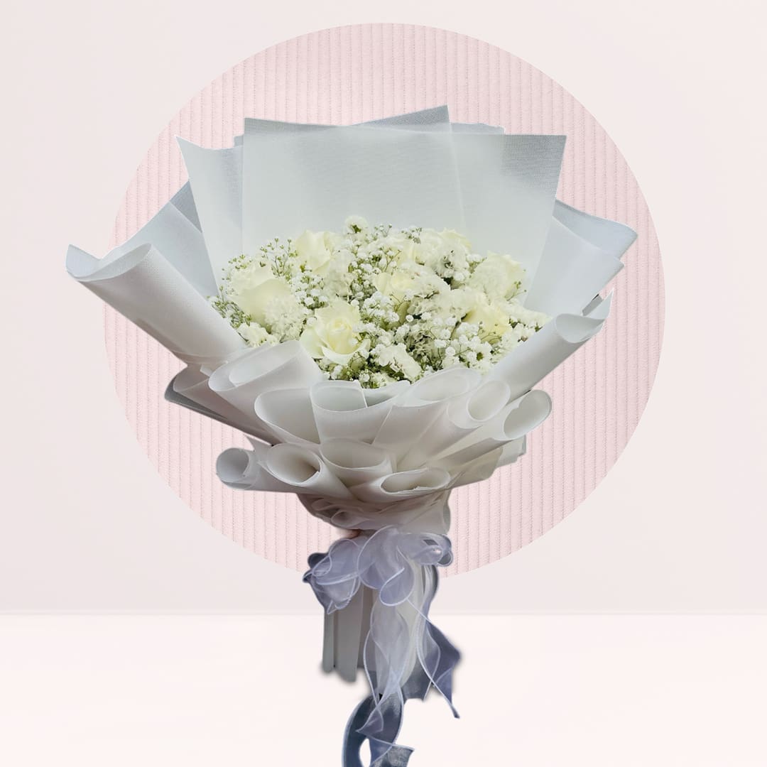 White-Rose-Bouquet-19-26 A hand bouquet of white roses and baby’s breath arranged elegantly on a table.
