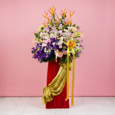 A vibrant flower arrangement featuring Eustoma, Hydrangea, and Orchids on a red pedestal for a grand opening display.