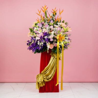 A vibrant flower arrangement featuring Eustoma, Hydrangea, and Orchids on a red pedestal for a grand opening display.
