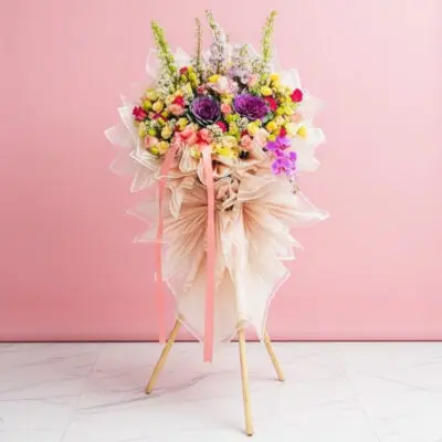 A grand opening flower stand featuring 20 assorted roses, 20 eustoma, 2 lilies, and 1 phalaenopsis against a pink wall.
