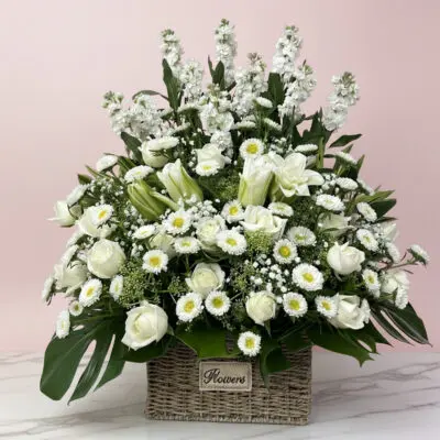 A basket filled with white sympathy flowers .