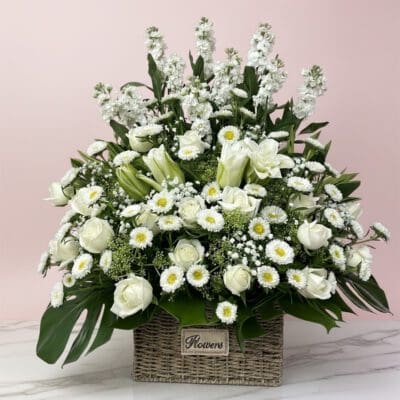 A basket filled with white sympathy flowers .