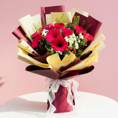 A vibrant bouquet of red and white flowers set against a soft pink background.