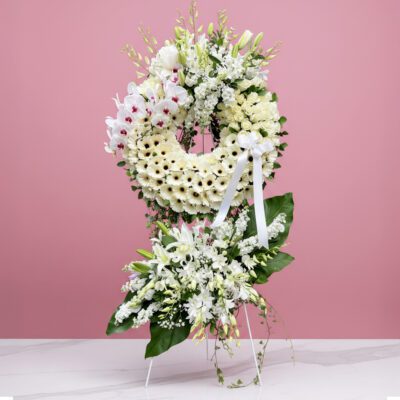 A white floral wreath adorned with various flowers and lush greenery