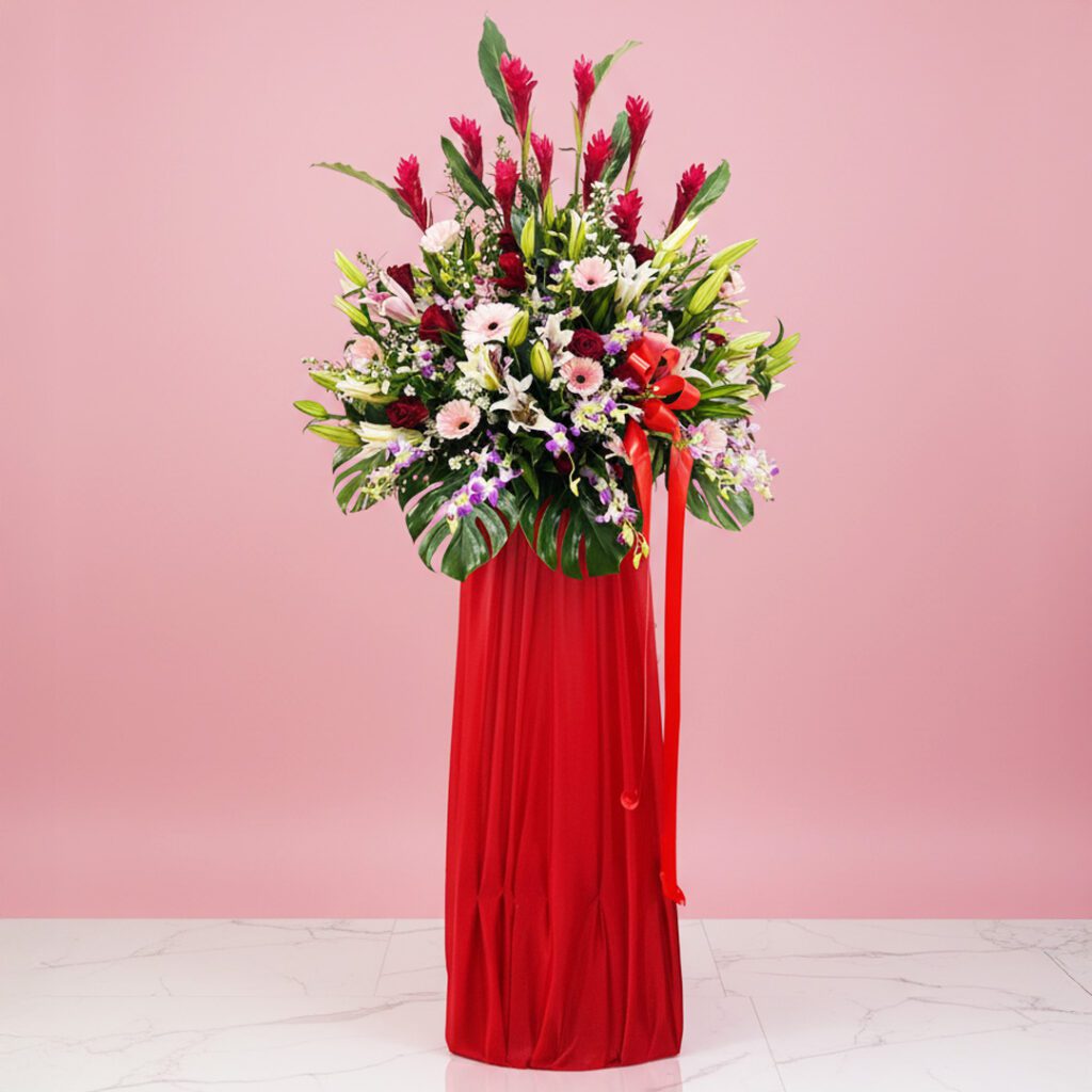 A decorative red vase with a floral arrangement and ribbon, designed for a grand opening stand display.