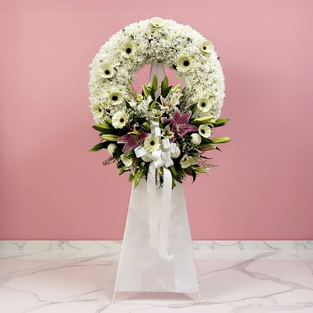 Forever in Our Hearts Floral Tribute-000012 A white floral wreath adorned with colorful flowers and a delicate ribbon