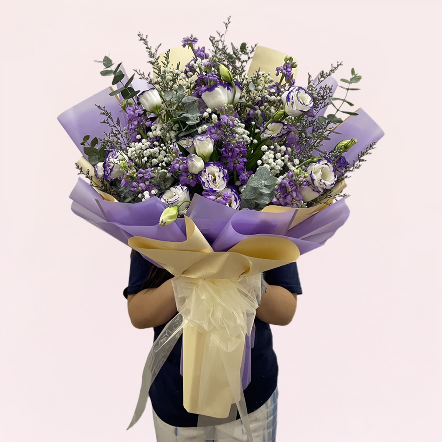 Lavender Dreams Bouquet-01-21 A person holding a bouquet of purple and white flowers, showcasing a mix of blooms and greenery.
