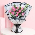 A lush hand bouquet featuring 10 pink roses, representing fresh beginnings and conveying a sense of tranquility and elegance.