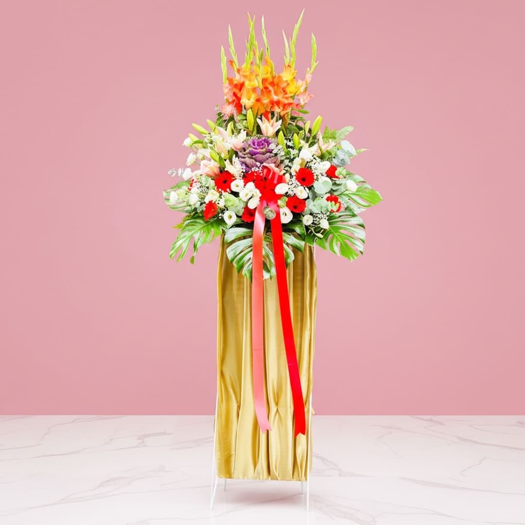Colorful Bloom Display-04-10 A grand opening stand featuring a tall vase with a mix of Gerbera, Eustoma, and Lilies, tied with a ribbon.