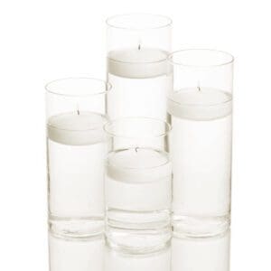 Four cylindrical glass vases filled with water and floating candles. The vases are arranged in different sizes, with the largest one in the back and the smallest one in the front.