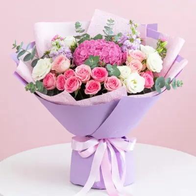 A bouquet of pink and white roses arranged in a purple box, showcasing a vibrant floral display.