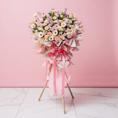 A grand opening flower stand featuring pink and white Gerbera, roses, orchids, and Eustoma in an elegant arrangement.