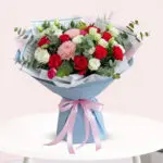 A vibrant bouquet of red and white flowers arranged elegantly on a wooden table.