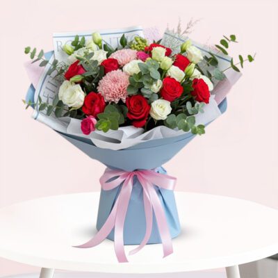 A vibrant bouquet of red and white flowers arranged elegantly on a wooden table.