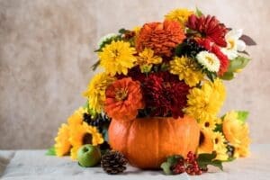 beautiful-autumn-bouquet-yellow-red-flowers-pumpkin arrangerd on a table