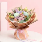 A colorful bouquet of flowers arranged in a paper bag, placed on a wooden table.