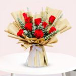 A vibrant bouquet of red roses arranged elegantly on a wooden table.