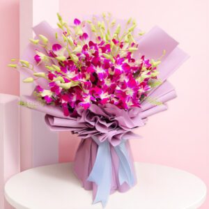 A bouquet of purple orchids, red roses, and eucalyptus leaves wrapped and showcasing nature's beauty.