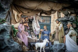 A Nativity scene depicting the birth of Jesus. The figures include Mary, Joseph, the baby Jesus, shepherds, and the three wise men. The scene is set in a stable with a manger, surrounded by animals. The overall impression is one of peace and reverence.
