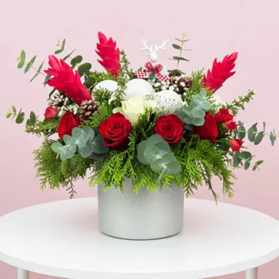 A white vase filled with vibrant red and white flowers, elegantly arranged for a decorative display.