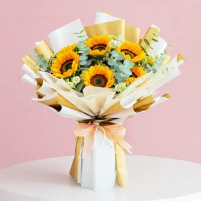 A vibrant bouquet of sunflowers tied with a gold ribbon, showcasing bright yellow petals and lush green leaves.