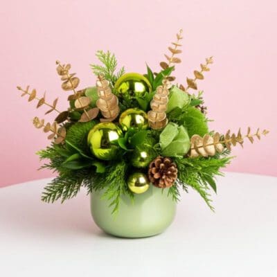 A green vase adorned with gold ornaments and pine cones, designed as a festive Christmas centerpiece.