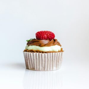 The cupcake is topped with a swirl of chocolate frosting and a dollop of green frosting, creating a visually appealing contrast.