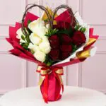 A bouquet of red and white roses arranged in a matching red and white vase.