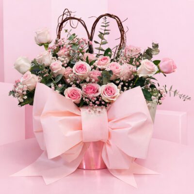 A pink bouquet featuring pink roses and greenery arranged in a matching pink vase.