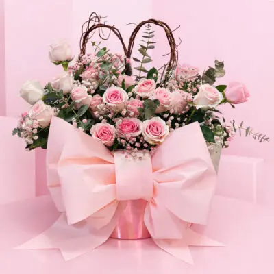 A pink bouquet featuring pink roses and greenery arranged in a matching pink vase.