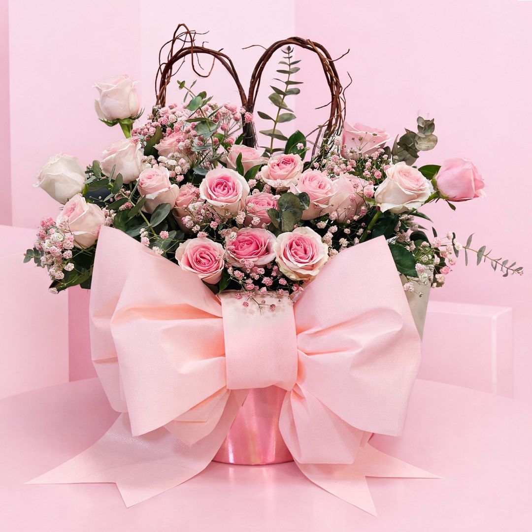 blush-romance-bouquet-2026 A pink bouquet featuring pink roses and greenery arranged in a matching pink vase.