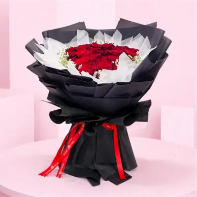 A vibrant bouquet of red roses surrounded by delicate white baby's breath flowers.