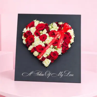 Heart-shaped arrangement of red and white roses, symbolizing love and affection, set against a neutral background.