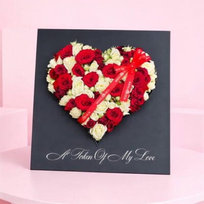 Heart-shaped arrangement of red and white roses, symbolizing love and affection, set against a neutral background.