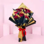 A bouquet of vibrant red roses elegantly wrapped in shimmering gold foil.