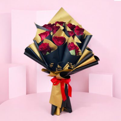 A bouquet of vibrant red roses elegantly wrapped in shimmering gold foil.