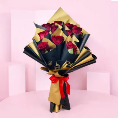 A bouquet of vibrant red roses elegantly wrapped in shimmering gold foil.
