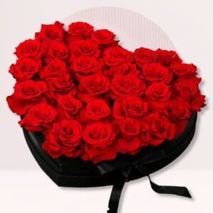 A heart-shaped box filled with a large arrangement of vibrant red roses