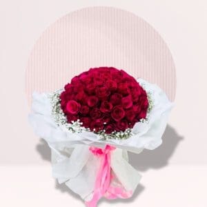 A lush, rounded bouquet of deep red roses is presented against a light-colored background with a semi-circular design. The roses are tightly packed, forming a dense, dome-shaped arrangement.