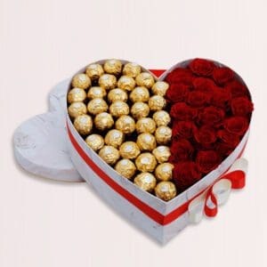 A heart-shaped box divided in half, filled with gold-wrapped chocolates on one side and red roses