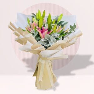 A bouquet of pink and white lilies with green stems, wrapped in cream and white paper, tied with a ribbon,
