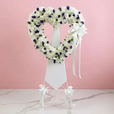Heart-shaped wreath adorned with purple and white flowers, symbolizing love and beauty.