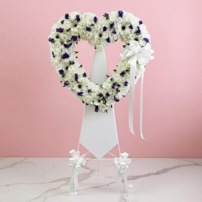 Heart-shaped wreath adorned with purple and white flowers, symbolizing love and beauty.