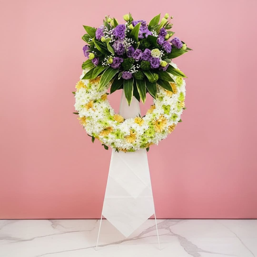 Graceful Floral Stand-01-11-25 A floral wreath composed of purple and white blooms, elegantly positioned on a stand.