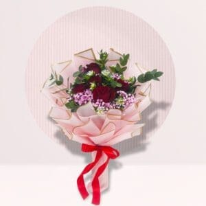 bouquet of flowers, wrapped in pink paper and tied with a red ribbon, against a light pink background with a white circle behind it. The bouquet contains red roses, white daisies, and sprigs of green leaves. The overall aesthetic is soft and romantic