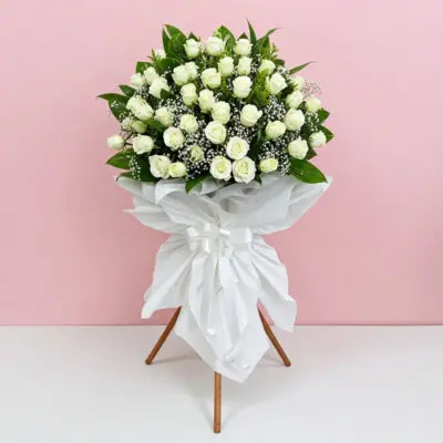 A bouquet of white roses elegantly arranged on a decorative stand.