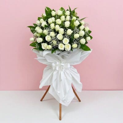 A bouquet of white roses elegantly arranged on a decorative stand.