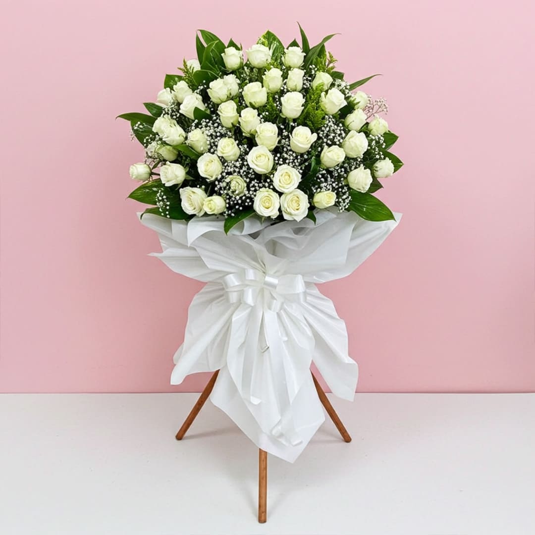 Whispers of Love-01 A bouquet of white roses elegantly arranged on a decorative stand.