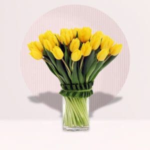 a bouquet of bright yellow tulips arranged in a clear glass vase