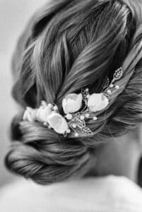 A delicate floral hairpin adorns an elegant updo in this close-up, black and white photograph